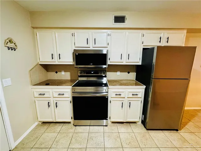 a kitchen with a stove top oven cabinets and a refrigerator