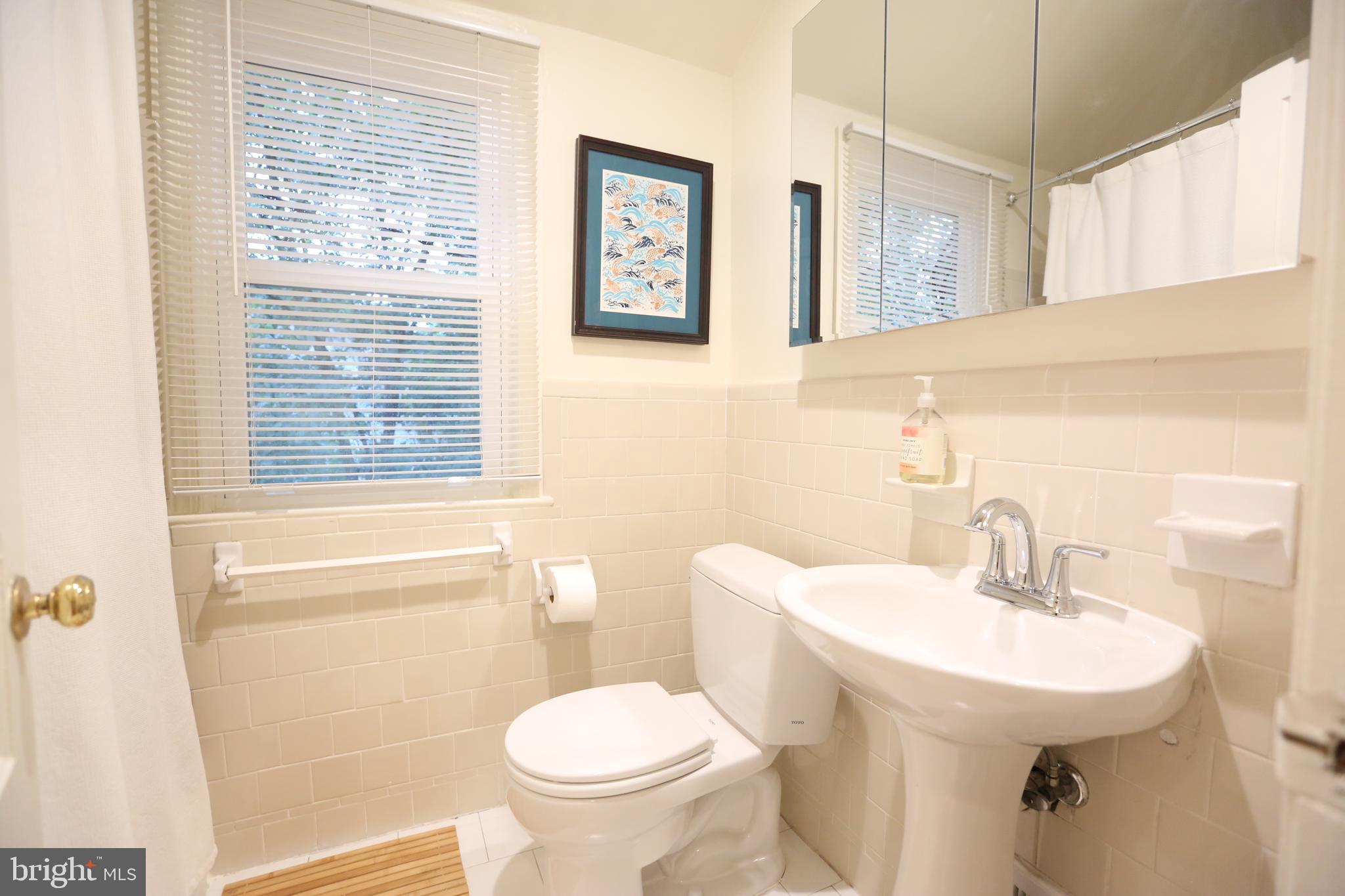 5862 Monticello Road Alexandria, VA 22303 - Photo 21 of 36 a bathroom with a sink a mirror a toilet and a window