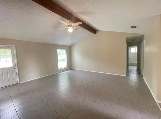 an empty room with windows and fan