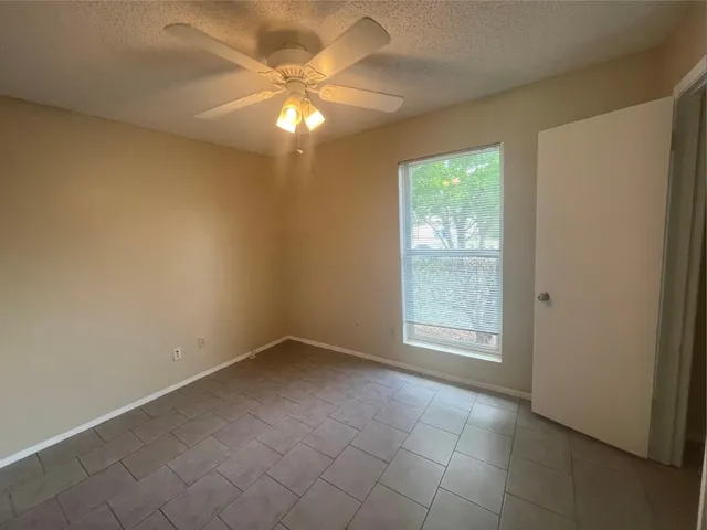 en empty room with windows and chandelier fan