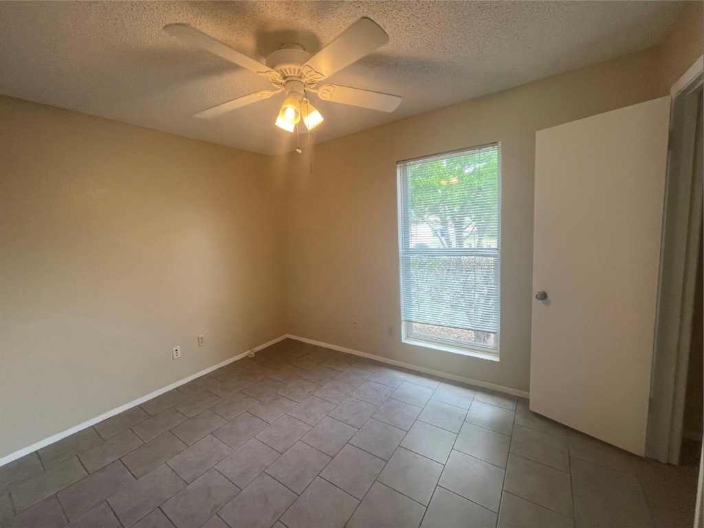 509 Riverwood Drive Cedar Park, TX 78613 - Photo 19 of 22 en empty room with windows and chandelier fan