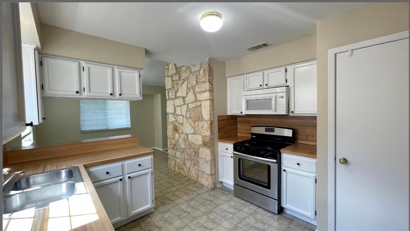 509 Riverwood Drive Cedar Park, TX 78613 - Photo 5 of 22 a kitchen with granite countertop white cabinets and stainless steel appliances