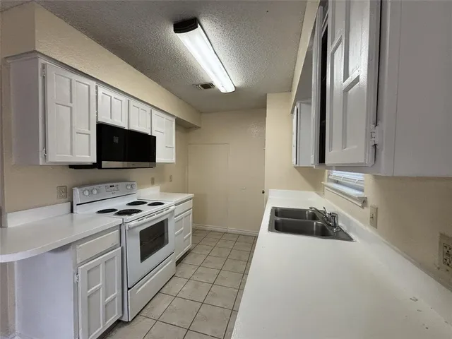 a kitchen with stainless steel appliances a stove a microwave and white cabinets
