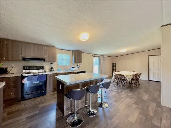 a kitchen with stainless steel appliances granite countertop a stove top oven a sink dishwasher a dining table and chairs with wooden floor