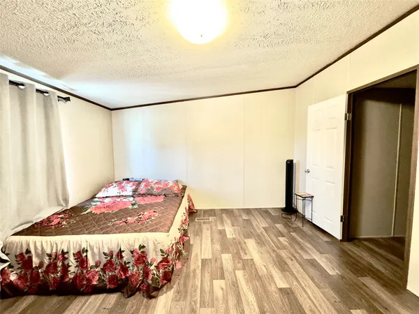 a bedroom with a bed and a dresser with wooden floor