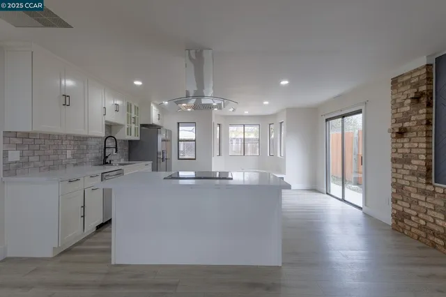 a view of kitchen with kitchen island wooden floor center island and stainless steel appliances