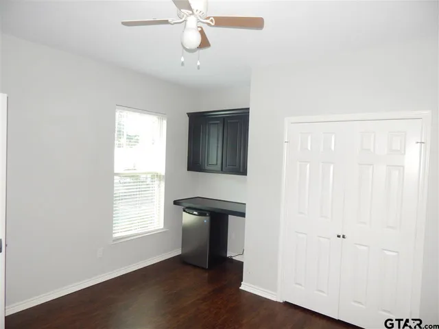 an empty room with wooden floor closet and windows