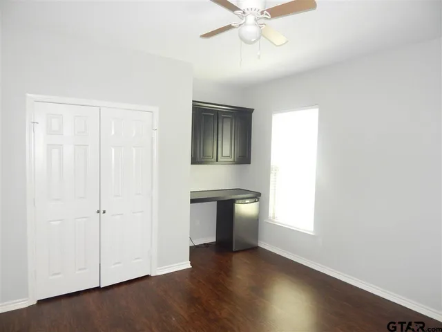 an empty room with wooden floor cabinet and windows