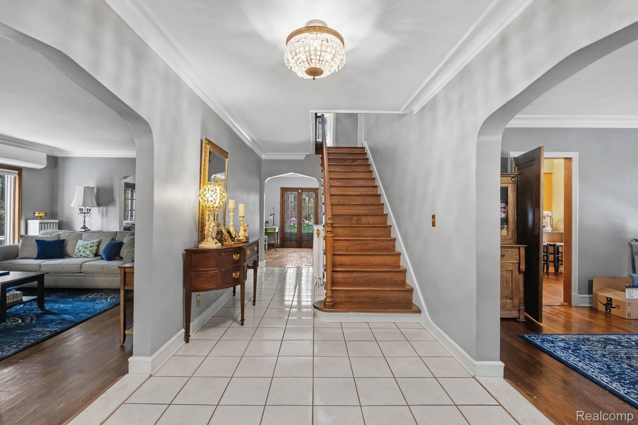 2030 Hampden Road Flint, MI 48503 - Photo 5 of 34 Foyer featuring tile flooring, a wood staircase with balusters, arched doorways, crown molding, and a chandelier