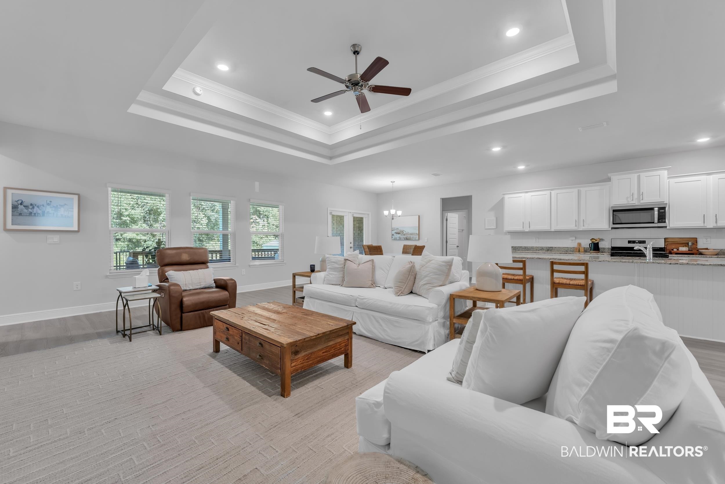 8774 Primland Boulevard Foley, AL 36535 - Photo 10 of 49 Living room featuring a raised ceiling, crown molding, recessed lighting, a chandelier, and light wood-style flooring