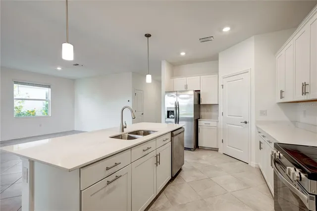 a kitchen that has a lot of white cabinets and stainless steel appliances
