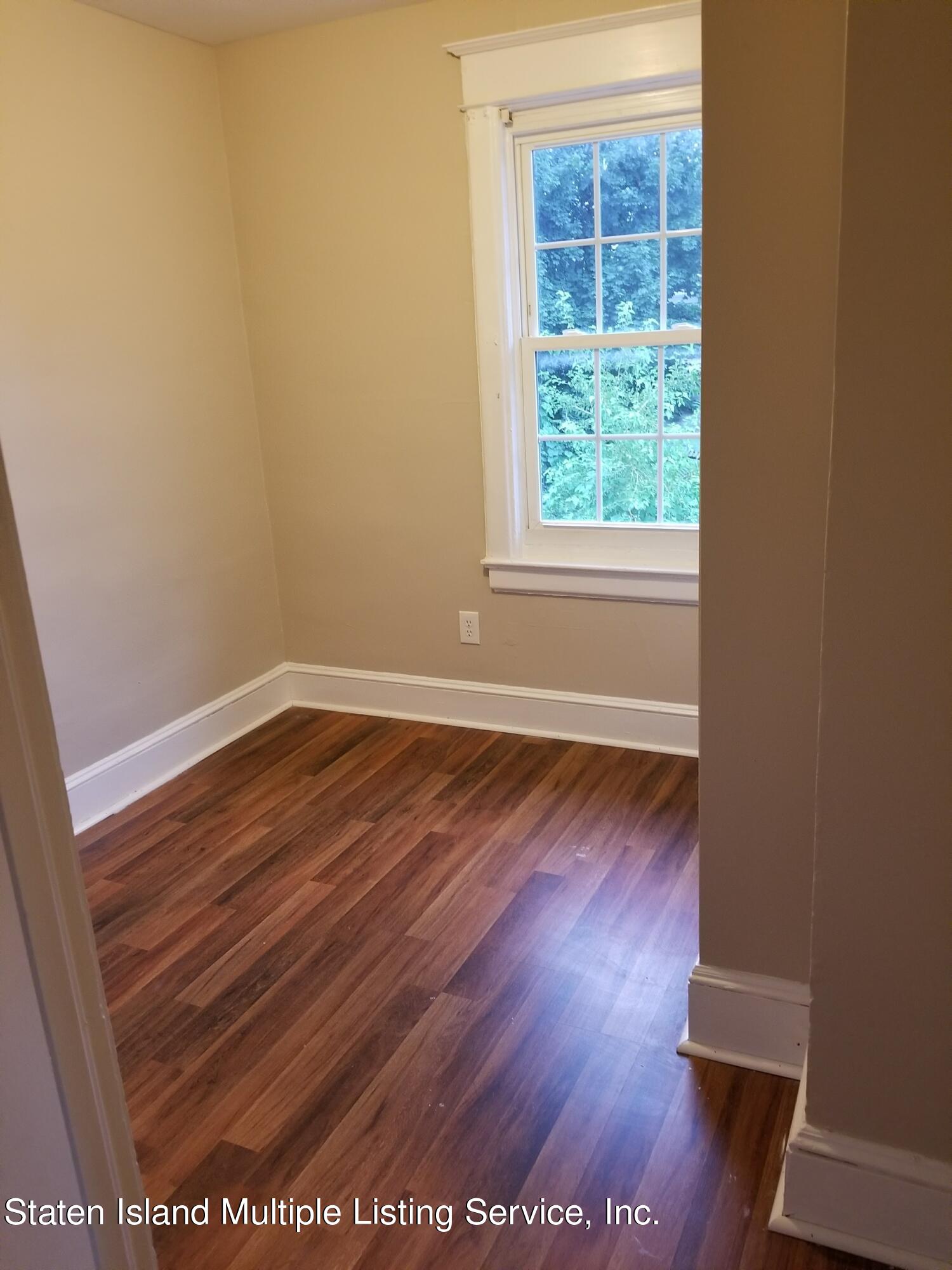 67 New Street Staten Island, NY 10302 - Photo 7 of 13 an empty room with wooden floor and windows