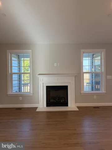 an empty room with wooden floor fireplace and windows
