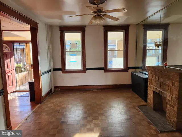 wooden floor in an empty room with a fireplace and a window