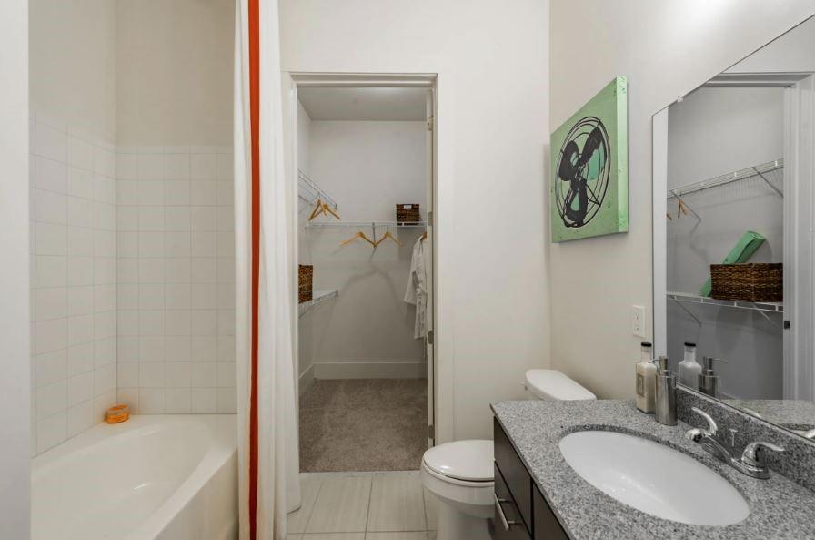 1391 Collier Road Northwest, Unit 2105 Atlanta, GA 30318 - Photo 13 of 43 a bathroom with a granite countertop sink toilet and shower