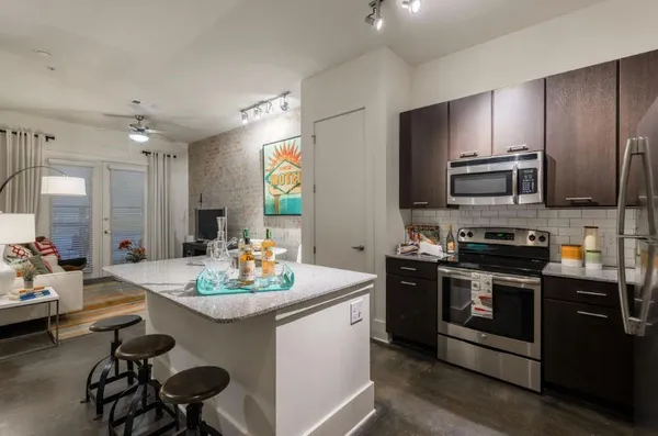 a kitchen with stainless steel appliances kitchen island granite countertop a stove a sink and a refrigerator