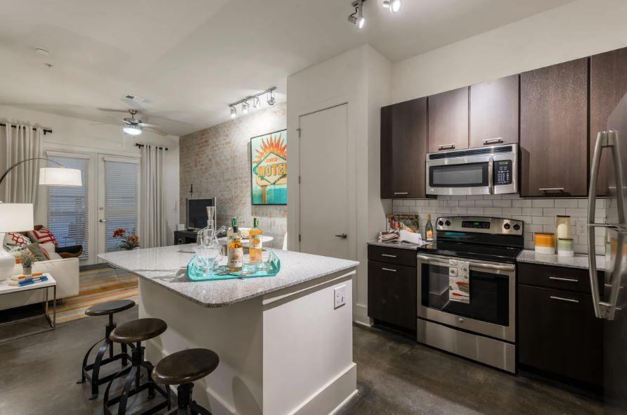 1391 Collier Road Northwest, Unit 2105 Atlanta, GA 30318 - Photo 2 of 43 a kitchen with stainless steel appliances kitchen island granite countertop a stove a sink and a refrigerator