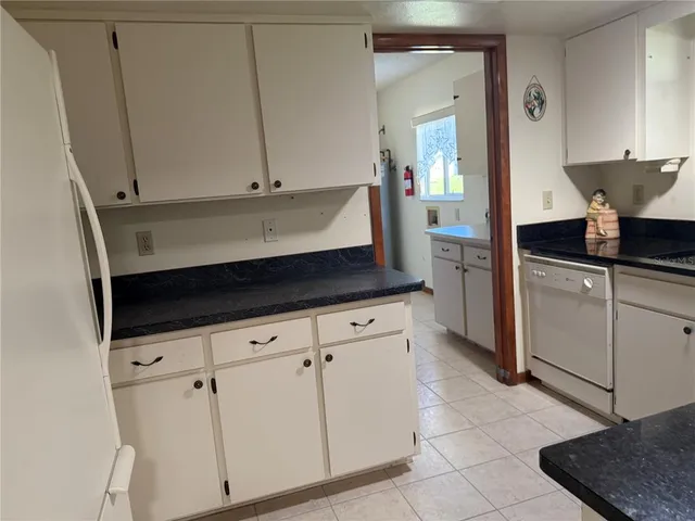a kitchen with granite countertop white cabinets and white appliances