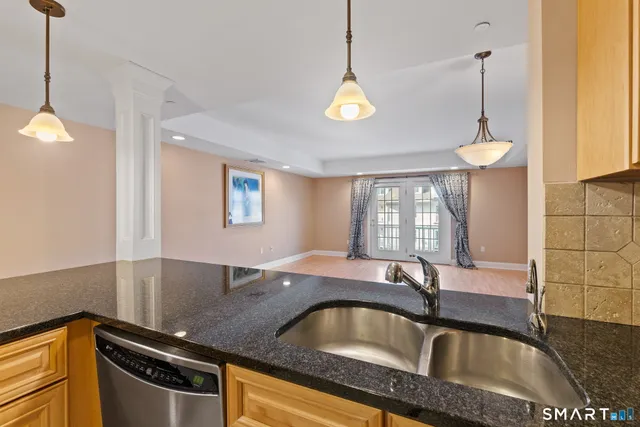 a kitchen with stainless steel appliances granite countertop a sink a counter space and a window