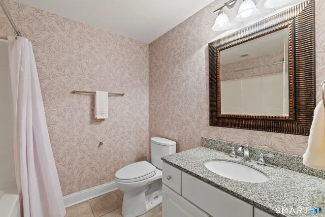 a bathroom with a granite countertop toilet a sink and a mirror