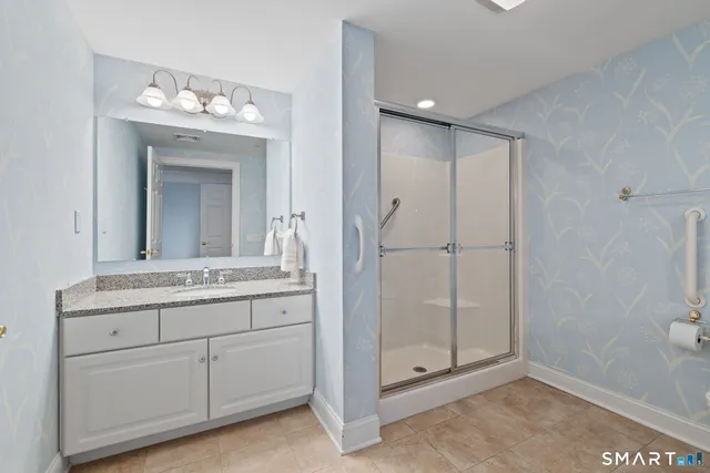 a bathroom with a granite countertop sink a mirror and a shower