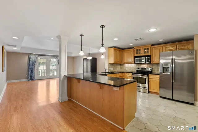 a kitchen with stainless steel appliances granite countertop a refrigerator a sink a stove and oven