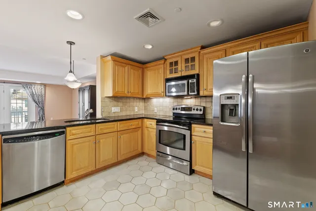 a kitchen with stainless steel appliances granite countertop a refrigerator a sink a stove with cabinets