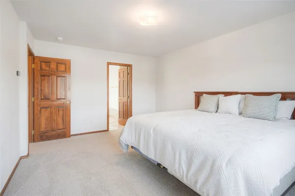 a spacious bedroom with a bed and wooden floor