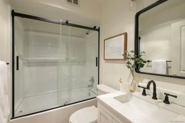 a bathroom with a shower sink vanity mirror and toilet