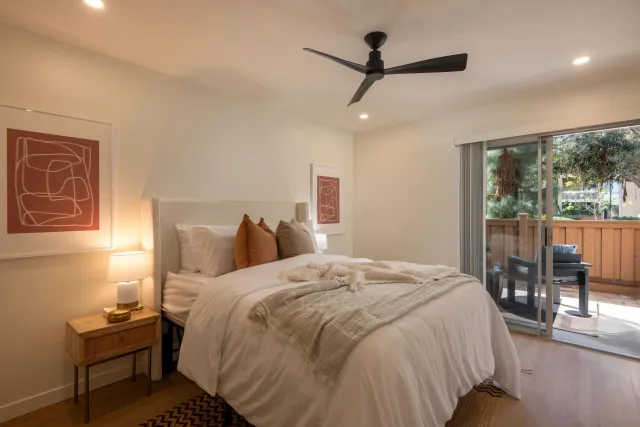 a bedroom with a bed a ceiling fan and a large window