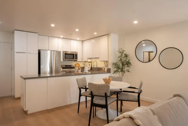 a kitchen with stainless steel appliances granite countertop a dining table chairs stove refrigerator and cabinets