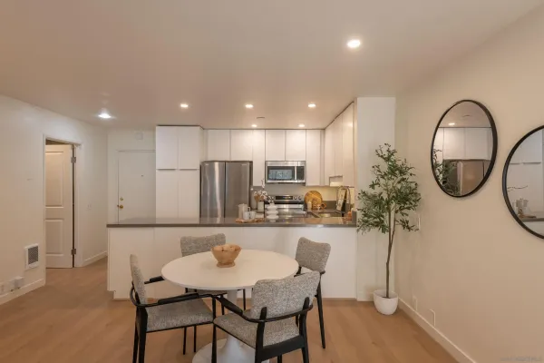 a kitchen with stainless steel appliances kitchen island granite countertop a dining table chairs and a refrigerator