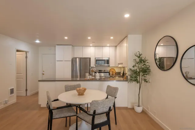 a kitchen with stainless steel appliances kitchen island granite countertop a dining table chairs and a refrigerator