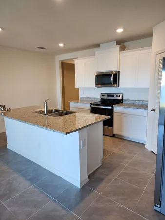 a kitchen with stainless steel appliances granite countertop a sink a stove top oven a counter space and cabinets