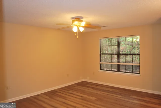 a view of empty room with wooden floor and fan