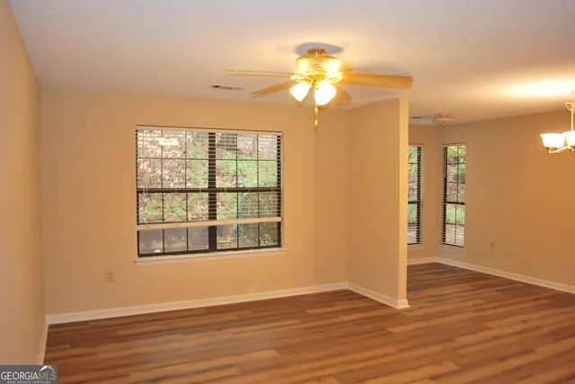 a view of empty room with wooden floor and fan