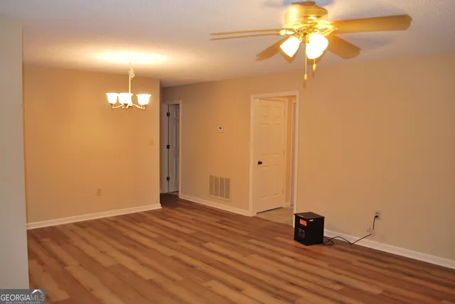 an empty room with wooden floor and fan