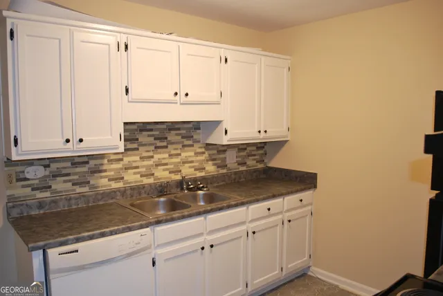 a kitchen with granite countertop white cabinets and a sink