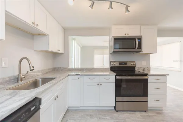 a kitchen with white cabinets and appliances