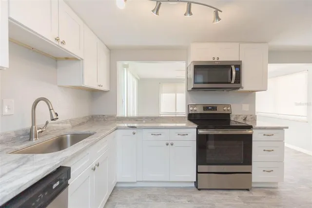 a kitchen with white cabinets and appliances