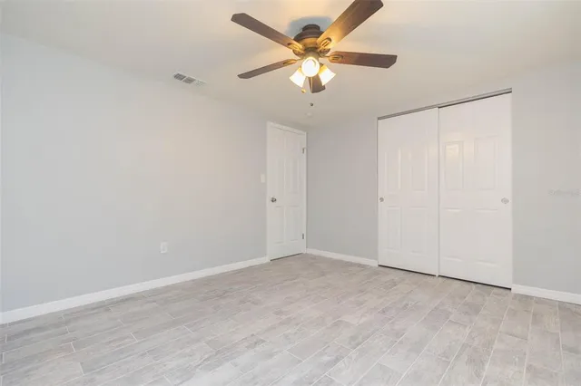 an empty room with a chandelier fan and closet area