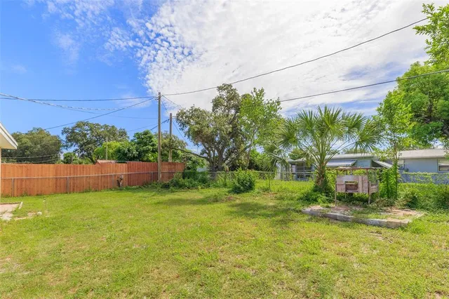 a view of a backyard with plants and wooden fence