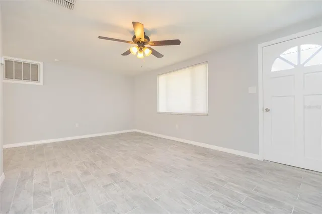 an empty room with windows and fan