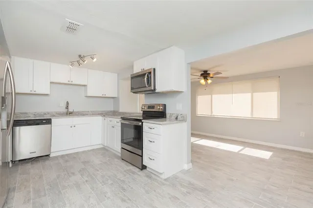 a kitchen with granite countertop white cabinets and white appliances