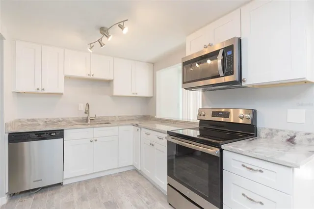 a kitchen with granite countertop white cabinets and black appliances