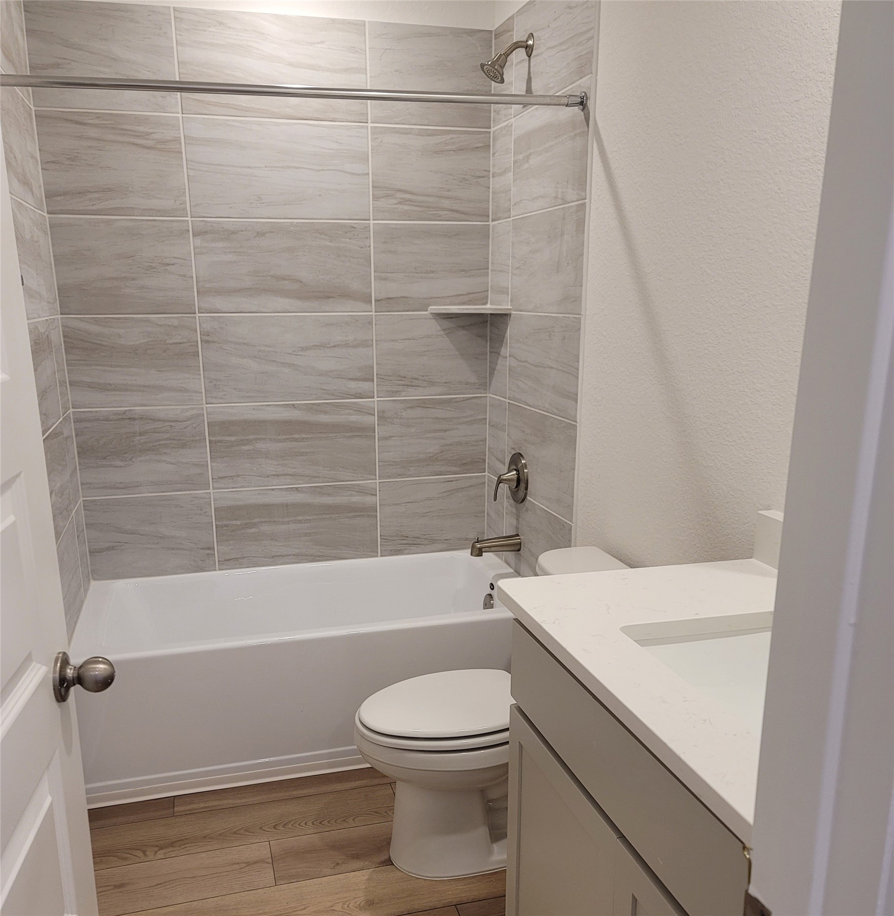 200 Callahan Loop Buda, TX 78610 - Photo 11 of 13 Bathroom featuring a white bathtub with a tiled shower surround, integrated shelf, and brushed nickel fixtures