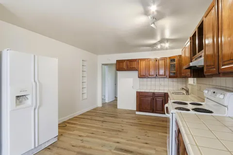 a kitchen with stainless steel appliances granite countertop a refrigerator a stove and a sink with cabinets