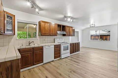 a kitchen with stainless steel appliances kitchen island granite countertop a sink cabinets and wooden floor