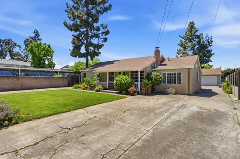 a front view of a house with a yard and potted plants