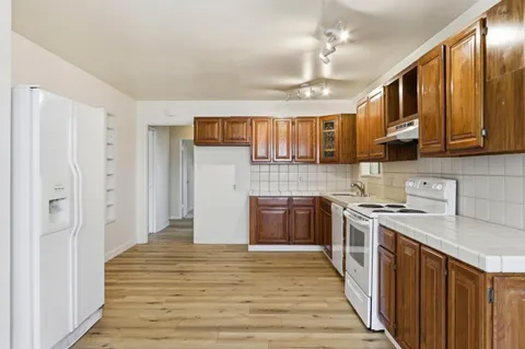 a kitchen with stainless steel appliances granite countertop a refrigerator a sink dishwasher a stove with wooden cabinets and floor